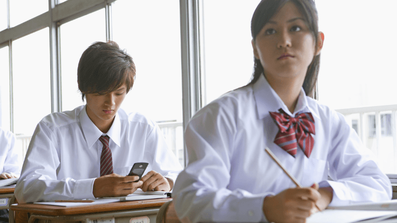 授業中にスマホを見る高校生
